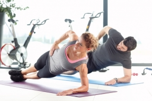 Portrait of a man and woman doing plank exercises at the gym.